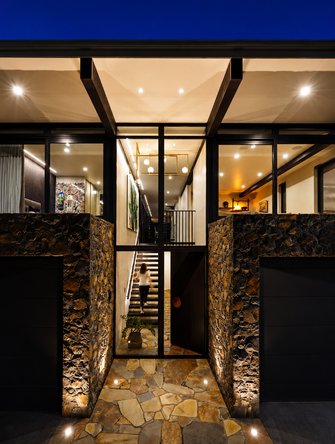 Architectural new-build entrance featuring stone walls, glazing and illuminated interior spaces